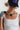 A woman wearing a statement necklace made of natural stones in gold, brown, and blue-gray, paired with a white ribbed tank top and a navy baseball cap-Vintage_Agate_Gold_Statement_Necklace-FleaStyle