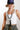 A woman wearing camouflage pants, a navy blue cap with a colorful butterfly embroidered patch and a smoky marbled beaded necklace with matte black beads and an oversized black fringe pendant  that gives  movement to the special vintage piece-Vintage_Beaded_Fringe_Pendant_Necklace