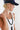 A woman wearing camouflage pants, a navy blue cap with a colorful butterfly embroidered patch and a smoky marbled beaded necklace with matte black beads and an oversized black fringe pendant  that gives  movement to the special vintage piece-Vintage_Beaded_Fringe_Pendant_Necklace