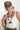 A woman wearing an olive green embroidered butterfly trucker hat  paired with a white ribbed tank top and a black beaded necklace with a gold ginkgo leaf pendant-FleaStyle