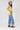 A woman wearing a  gold lace-trimmed flowy camisole top with feminine sholder ties paired with medium wash blue jeans with a relaxed wide-leg silhouette, brown boots, and a stone cowboy hat, offers the perfect blend of comfort-Medium_Wash_Cuffed_Wide_Leg_Jeans-FleaStyle