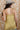 A woman wearing a  gold lace-trimmed flowy camisole top with feminine sholder ties paired with medium wash blue jeans with a relaxed wide-leg silhouette, brown boots, and a stone cowboy hat, offers the perfect blend of comfort-Medium_Wash_Cuffed_Wide_Leg_Jeans-FleaStyle