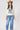 A woman wearing a camel cowboy hat,poncho-style top features an oversized batwing silhouette, vintage-inspired Free Bird graphic and sheer lace sleeves, and blue jeans, photographed against a light gray studio background--Free_Bird_Lace_Graphic_Tee_Poncho_Top_-_Ivory-FleaStyle.