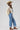 A woman shown from the back wearing a white top with sheer lace sleeves, paired with medium wash blue jeans with a relaxed wide-leg silhouette and a flattering high waist,  brown boots and cowboy hat, offers the perfect blend of comfort--Medium_Wash_Cuffed_Wide_Leg_Jeans-FleaStyle