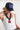 A woman wearing a navy blue trucker-style cap with a colorful butterfly patch on the front, and a chunky black sculptural link necklace finished with an oversized red heart pendant -Vintage_Resin_Heart_Link_Necklace-FleaStyle