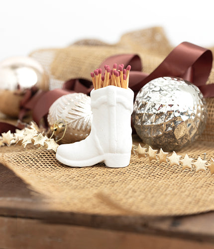 White boot-shaped match holder with matches on a decorative surface with ornaments-FleaStyle