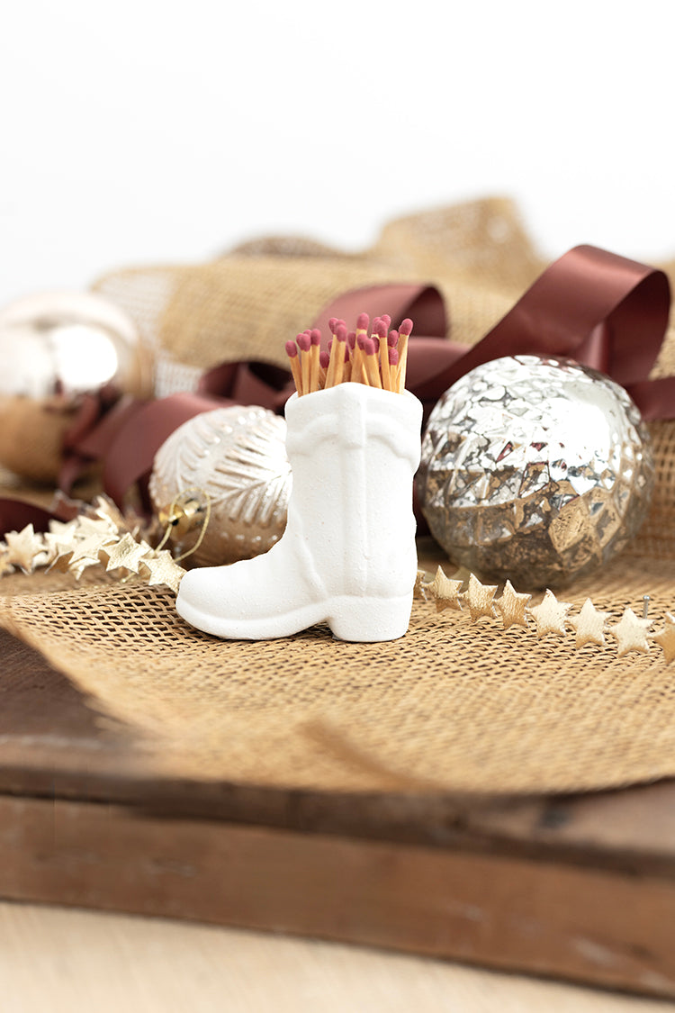 White boot-shaped match holder with matches on a decorative surface with ornaments-FleaStyle