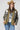 A woman wearing a western-style camo quilted jacket with white embroidered paisley patches, a graphic tee,  relaxed wide-leg silhouetted jean,  brown boots and camel cowboy hat, offers the perfect blend of stylized comfort-Camo_Quilted_Jacket_with_Paisley_Patches-FleaStyle