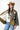 A woman wearing a western-style camo quilted jacket with white embroidered paisley patches, a graphic tee,  relaxed wide-leg silhouetted jean,  brown boots and camel cowboy hat, offers the perfect blend of stylized comfort-Camo_Quilted_Jacket_with_Paisley_Patches-FleaStyle