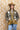 A woman wearing a western-style camo quilted jacket with white embroidered paisley patches, a graphic tee,  relaxed wide-leg silhouetted jean,  brown boots and camel cowboy hat, offers the perfect blend of stylized comfort-Camo_Quilted_Jacket_with_Paisley_Patches-FleaStyle