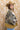 A woman wearing a western-style camo quilted jacket with white embroidered paisley patches, a graphic tee,  relaxed wide-leg silhouetted jean,  brown boots and camel cowboy hat, offers the perfect blend of stylized comfort-Camo_Quilted_Jacket_with_Paisley_Patches-FleaStyle