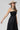 A woman wearing a black tiered strapless midi dress with a smocked bodice, paired with a beige flat-brim hat, turquoise necklace, and brown cowboy boots for a everyday casual elegance --Strapless_Mixed_Media_Midi_Dress_-_Black-FleaStyle