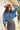 A woman wearing a distressed blue cropped denim jacket with raw frayed edges, a rust curled brim cowboy hat that's warm and spicy, and a brown studded skirt,  outdoors against a light-colored wooden barn-Rider Wool Cowboy Hat - Rust-FleaStyle