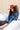 A woman wearing a distressed blue cropped denim jacket with raw frayed edges, a rust curled brim cowboy hat that's warm and spicy, and a brown studded skirt,  outdoors against a light-colored wooden barn-Rider Wool Cowboy Hat - Rust-FleaStyle