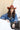 A woman wearing rust cowboy hat, a blue denim raw hemmed distressed cropped jacket, a sheer lace long sleeve top, and a long flared dark olive skirt with silver studs, standing outdoors in front of a yellow wooden barn door-Cropped_Distressed_Denim_Jacket-FleaStyle