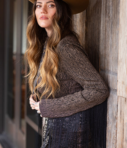 Woman wearing a metallic fringe minidress with a camel cowboy wool felt hat