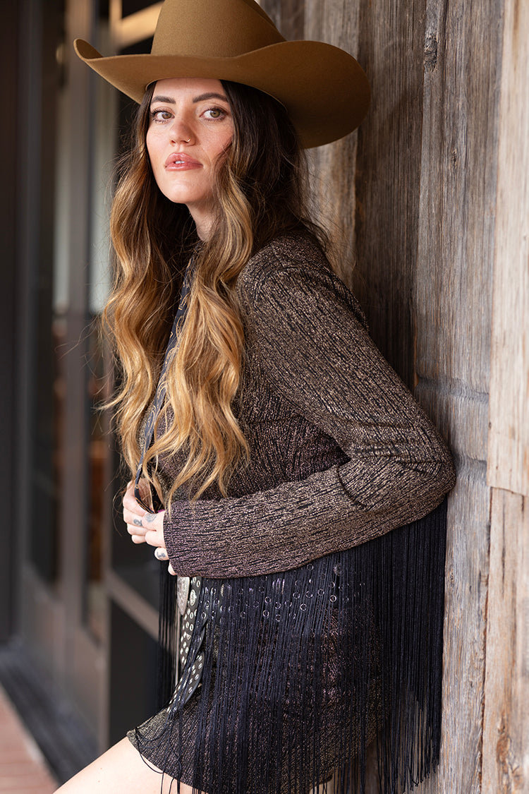 Woman wearing a metallic fringe minidress with a camel cowboy wool felt hat