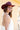 A woman wearing a maroon curl-brimmed cowboy hat and an ivory halter dress, posing in front of a light beige wooden barn wall-Rider_Wool_Cowboy_Hat_-_Maroon-FleaStyle.