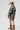 A woman wearing a beige and black leopard-print oversized denim jacket paired with a cream-colored shift dress, a beige flat brim hat, dark beaded necklace  and cowboy boots for a fun on the go look-Oversized_Leopard_Denim_Jacket-FleaStyle