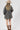 A woman wearing a beige and black leopard-print oversized denim jacket paired with a cream-colored shift dress, a beige flat brim hat, dark beaded necklace  and cowboy boots for a fun on the go look-Oversized_Leopard_Denim_Jacket-FleaStyle