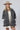A woman wearing a beige and black leopard-print oversized denim jacket paired with a cream-colored shift dress, a beige flat brim hat, dark beaded necklace  and cowboy boots for a fun on the go look-Oversized_Leopard_Denim_Jacket-FleaStyle