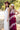 A woman wearing a maroon curl-brimmed cowboy hat and an ivory halter dress, posing in front of a light beige wooden barn wall-Rider_Wool_Cowboy_Hat_-_Maroon-FleaStyle.