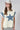 A woman wearing a cream-colored sleeveless top with a large blue star patches on front and back and  blue patterned lace appliques on the shoulders, paired with a beige cowboy hat and a Denim_Star_Patchwork_Sleeveless_T-Shirt-FleaStyle