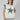 A woman wearing a cream-colored sleeveless top with a large blue star patch and  blue patterned lace appliques on the shoulders, paired with a beige cowboy hat and a Denim_Star_Patchwork_Sleeveless_T-Shirt-FleaStyle