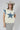 A woman wearing a cream-colored sleeveless top with a large blue star patch and  blue patterned lace appliques on the shoulders, paired with a beige cowboy hat and a Denim_Star_Patchwork_Sleeveless_T-Shirt-FleaStyle