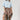 A woman wearing a light blue cropped knit sweater and a brown plaid high-low skirt with frayed edges, wearing a tan cowboy hat --Plaid_Asymmetrical_Tiered_Midi_Skirt-FleaStyle