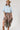A woman wearing a light blue cropped knit sweater and a brown plaid high-low skirt with frayed edges, wearing a tan cowboy hat --Plaid_Asymmetrical_Tiered_Midi_Skirt-FleaStyle