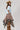 A woman wearing a light blue cropped knit sweater and a brown plaid high-low skirt with frayed edges, wearing a tan cowboy hat --Plaid_Asymmetrical_Tiered_Midi_Skirt-FleaStyle