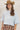 A woman wearing a light blue cropped knit sweater and a brown plaid high-low skirt with frayed edges, wearing a tan cowboy hat --Plaid_Asymmetrical_Tiered_Midi_Skirt-FleaStyle