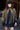A woman wearing a black cowboy hat, an ornate long beaded black and gold fringe caplet over a black lace tunic standing in a rustic barn-Beaded_Fringe_Capelet_-_Gold-FleaStyle
