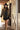 A woman wearing a black cowboy hat, an ornate long beaded black and gold fringe caplet over a black lace tunic standing in a rustic barn-Beaded_Fringe_Capelet_-_Gold-FleaStyle