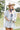 Woman in a Short-Sleeve-Striped-Romper-Blue-Fleastyle, blue bandana and cowboy hat walking on a soccer field.