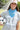 Woman holding a soccer ball with a blue bandana and white cap wearing a Striped_Texas_Graphic_T-Shirt_-_Dusty_Blue-Fleastyle
