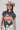 A woman wearing a cotton graphic tee featuring a lived-in charcoal wash, relaxed fit and bold 'She's From Texas Can Tell' graphic design, paired with a beige cowboy hat and white toile skirt-She_s_From_Texas_Graphic_T-Shirt_-_Red-FleaStyle