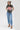 A woman wearing a dark gray graphic t-shirt with a red and white 'She's from Texas' design, paired with a medium wash blue jeans with a relaxed wide-leg silhouette and a flattering high waist,  brown boots and cowboy hat for the perfect blend of comfort--Medium_Wash_Cuffed_Wide_Leg-Jeans-FleaStyle