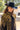 A woman wearing a black cowboy hat, an ornate long beaded black and gold fringe caplet over a black lace tunic
standing in a rustic barn-Beaded_Fringe_Capelet_-_Gold-FleaStyle