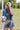Woman holding a soccer ball wearing a cap with a 'Futbol Y'all' design and a Denim-Star-Graphic-T-Shirt-Dusty-Blue-Fleastyleon a grassy field .