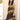 A woman wearing a sleeveless brown maxi dress featuring contrast olive lace detailing throughout for a rich, vintage-inspired feel paired with and a stone/beige cowboy hat, standing outdoors in front of a barn-Lace_Trim_Maxi_Dress_-_Brown_Chartreuse-FleaStyle