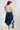 A woman wearing a western-style outfit featuring a tan fringe shrug over a beige top, a dark denim midi a-line skirt, and brown cowboy boots, with a  maroon cowboy hat,-Dark Denim A-Line Midi Skirt-FleaStyle