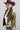 A woman wearing a maroon cowboy hat, olive green western-style jacket with cream and turquoise accents, a white ribbed crop top, blue jeans, and a pair of oval silver-toned concho-style earrings-earrings with turquoise-colored inlay stones Western_Inspired_Scalloped_Earrings-FleaStyle.