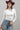 A woman wearing a classic long-sleeve tee features a flattering, fitted silhouette with an elegant boat neckline worn alone or styled as an effortless layering piece--Boat_Neck_Long_Sleeve_Top_-_Ivory-FleaStyle