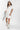 Woman wearing an ivory Floral-Embroidery-Cut-Out-Mini-Dress, cowboy boots, and a white cap with 'Texas' text on a white background-Fleastyle