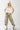 Woman wearing a beige Texas-Short-Sleeve-Ribbed-T-Shirt-Light-Khaki- white cap with a patch and Baggy-Fit-Camo-Pants-with-Paint-Splatter-Detail-Fleastyle 