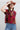 A woman wearing a maroon short-sleeve crewneck sweater with a red, orange, and white tiger print, paired with blue jeans and a rust cowboy hat-Tiger_Tapestry_Short-Sleeve_Sweater-FleaStyle