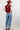 A woman wearing a maroon short-sleeve crewneck sweater with a red, orange, and white tiger print, paired with blue jeans, turquoise elongated concho earrings and a rust cowboy hat-Tiger_Tapestry_Short-Sleeve_Sweater-FleaStyle