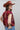 A woman wearing a maroon short-sleeve crewneck sweater with a red, orange, and white tiger print, paired with blue jeans, turquoise elongated concho earrings and a rust cowboy hat-Tiger_Tapestry_Short-Sleeve_Sweater-FleaStyle